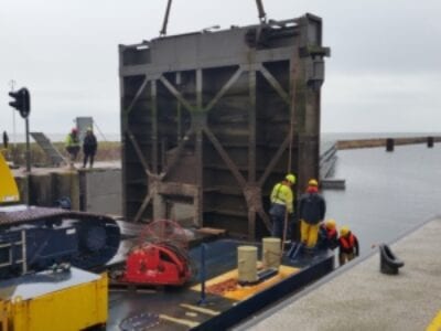 Werkzaamheden door het uithijsen van de sluisdeuren. Er is een boot bezig om een sluisdeur uit het water te takkelen.