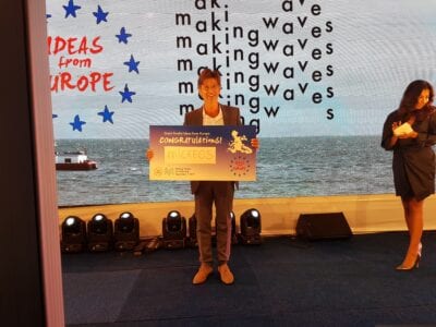 Micreos krijgt een prijs voor de beste innovatie van Nederland. Een man staat op het podium en houdt een cheque omhoog.