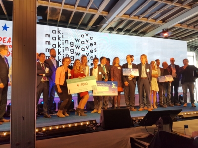 Alle prijswinnaars tijdens het evenement bij Making Waves staan op een rij. Ze houden allemaal cheques omhoog.