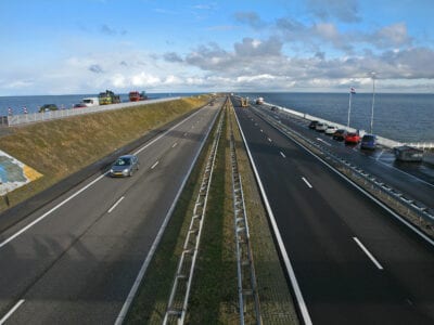 Weg van de Afsluitdijk met 1 auto en water aan beide kanten