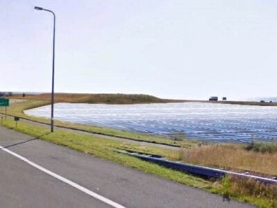 Zonnepanelen die bij de afslag komen. Deze foto is een impressie. We zien een afslag bij het tankstation. Aan de rechterkant in het gras liggen rijen met zonnepanelen.
