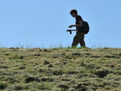 Wandelaar op het Zuiderzeepad. Wij kijken op de dijk uit. Boven op de dijk loopt een man en daarboven zie je lucht.