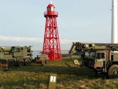 Verplaatsing van de lichtopstand bij Den Oever. We zien twee legervoertuigen een rode vuurtoren verplaatsen.