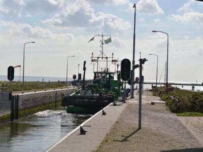 Boot manoeuvreert voorzichtig door de Schutssluis. Op de achtergrond zie je het IJsselmeer