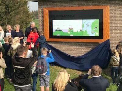 Woudagemaal breidt expositie uit met Afsluitdijk. Presentatie met kinderen die een scherm onthullen met tekeningen.