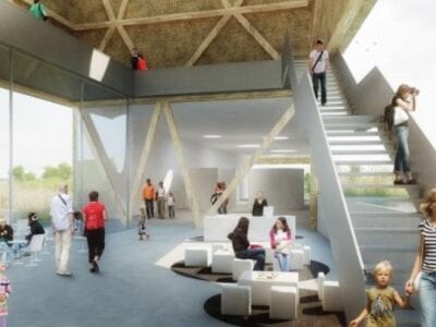 Impressie van het beleefcentrum. We zien een hal met rechts een trap. Er lopen veel mensen en kinderen.