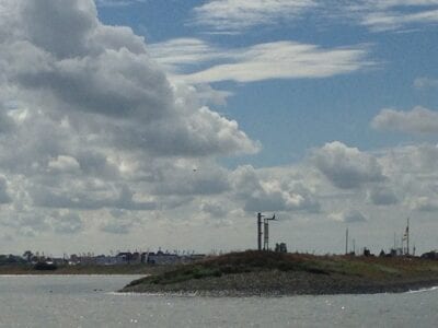Wij kijken uit over het water. In de verte zie je land met industrie.