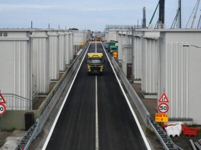 Op de foto zien we de weg van de Afsluitdijk. Op de weg zie je een vrachtwagen