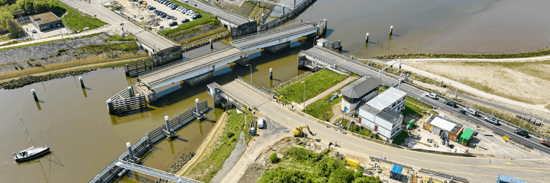 Luchtfoto op land met een aantal wegen. Water en draaibruggen die open staan.