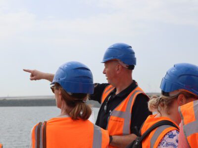 Meerdere personen met bouwhelmen en oranje hesjes